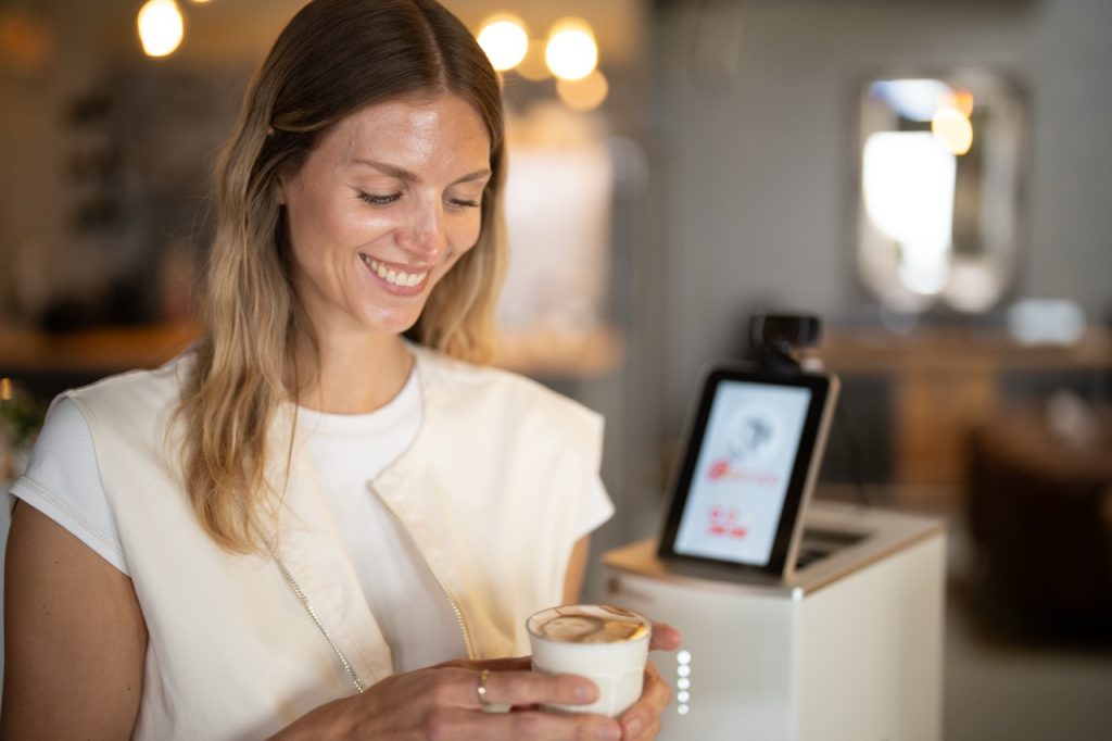 Barista serviert Cappuccino mit gedrucktem Logo auf dem Milchschaum